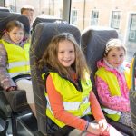 Kinder mit Warnweste im Schulbus