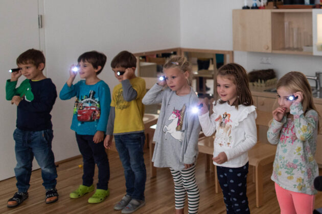 Kinder mit Taschenlampen im Klassenraum