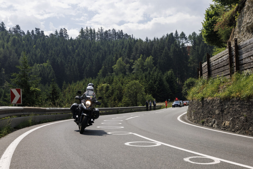 Ein Motorrad fährt auf einer Landstraße in eine Kurve, neben Ellipsen-förmigen Bodenmarkierungen.