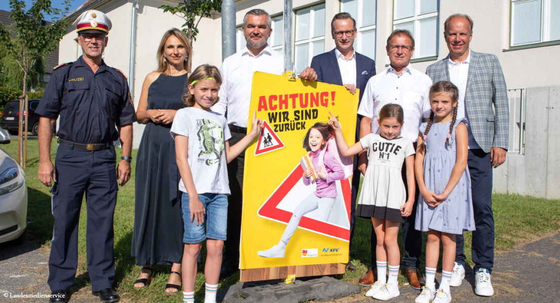 Politiker*innen und Schüler*innen vor dem Plakat