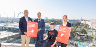 ÖBB-Infrastruktur Vorstand Johann Pluy, KFV-Geschäftsführer Mag. Christian Schimanofsky, Nino Laitinen und Oberärztin Dr. Viktoria König stehen mit 2 Plakat-Sujets vor der Skyline des Wiener Praters