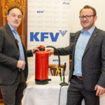 Dr. Armin Kaltenegger (KFV) und Dr. Günther Schwabegger (BVS OÖ) bei der Pressekonferenz. Zwischen ihnen steht ein Feuerlöscher, hinter ihnen ein Roll-Up mit dem Logo des KFV.