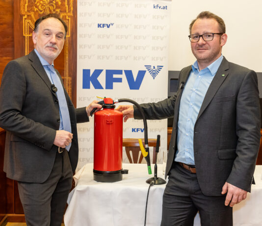 Dr. Armin Kaltenegger (KFV) und Dr. Günther Schwabegger (BVS OÖ) bei der Pressekonferenz. Zwischen ihnen steht ein Feuerlöscher, hinter ihnen ein Roll-Up mit dem Logo des KFV.