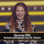 KFV-Mitarbeiterin Simone bei der Quiz-Show. Sie steht an einem Podium und lacht herzlich. Sie hat lange, lockige, rötliche Haare und trägt schwarz-weiß gemusterte Kleidung. Sie trägt ein Mikrofon an ihrer rechten Wange bzw. hinter ihrem rechten Ohr. Im Hintergrund sind gelbe Linien und Lichter zu sehen. Im Bild eingeblendet ist der Text: "Simone (24) Verkehrspädagogin aus St. Stefan"