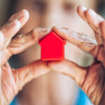 Eine ältere Dame hält ein Spielzeughaus in der Hand