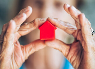 Eine ältere Dame hält ein Spielzeughaus in der Hand