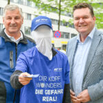 Komm. Rat Peter Engelbrechtsmüller, Vorsitzender der zuständigen AUVA-Landesstelle für Wien/NÖ/Burgenland, ein "kopfloser" Aktionsmitarbeitender, der einen Flyer in Richtung Kamera aussteckt und Dipl.-Ing. Christian Kräutler (KFV).