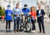 Dipl.-Ing. Christian Kräutler (KFV), Mag.a Maria Lesterl (Direktorin der AUVA-Landesstelle Linz) und Leonhard Zauner MLS (Vorsitzender des Landesstellenausschusses) stehen in Linz am Hauptplatz mit einem kopflosen Aktionsmitarbeitenden und einer kopflosen Radfahrer-Puppe.