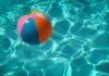 Ein bunter Wasserball in türkis-glitzerndem Poolwasser.