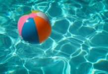 Ein bunter Wasserball in türkis-glitzerndem Poolwasser.