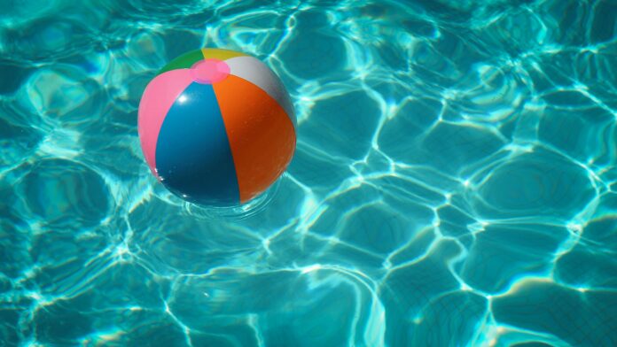 Ein bunter Wasserball in türkis-glitzerndem Poolwasser.