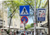 Eine Begegnungszone: Sichtbar sind die Passant*innen und die Schilder für die zu Fuß Gehenden und die begrünte Begegnungszone.