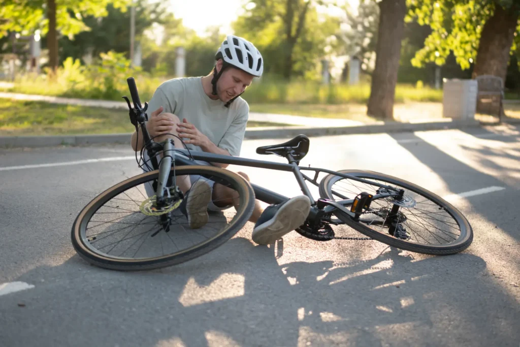 Mann mit Fahrradhelm sitzt nach einem Sturz auf der Straße