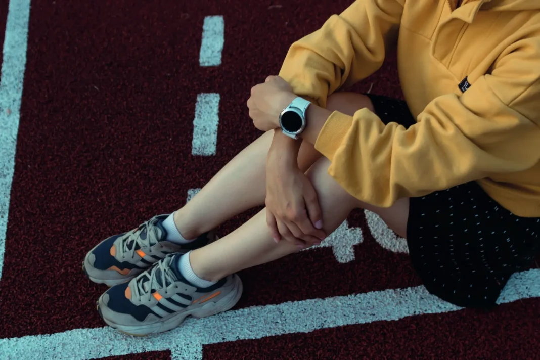 Person sitzt auf der Laufbahn und trägt eine Smartwatch