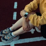 Person sitzt auf der Laufbahn und trägt eine Smartwatch