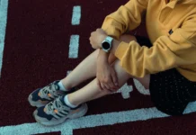 Person sitzt auf der Laufbahn und trägt eine Smartwatch