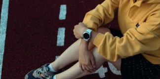 Person sitzt auf der Laufbahn und trägt eine Smartwatch