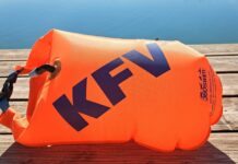 Eine orange Schwimmboje mit KFV-Logo liegt aufgeblasen auf dem Holzsteg vor einem spiegelglatten See.
