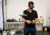 Ein Mann mit VR-Brille lenkt eine Drohne vor sich in einem Raum.