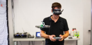 Ein Mann mit VR-Brille lenkt eine Drohne vor sich in einem Raum.
