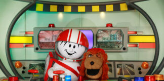 HELMI und Sokrates im Schwuppodrom. Sie lächeln beide in die Kamera, Sokrates zwinkert.