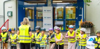 Eine Klasse im Hof mit Warnwesten und Helmen.