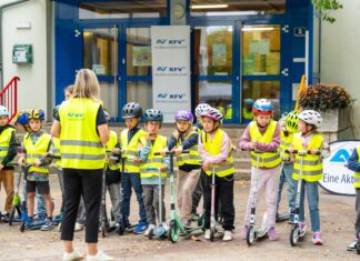 Workshop „Sicheres Rollern“ für mehr Sicherheit am Tretroller Eine Klasse im Hof mit Warnwesten und Helmen.
