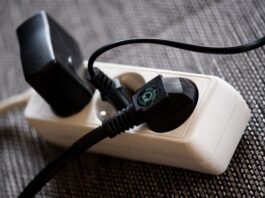 Eine Mehrfachsteckdosen-Leiste mit 3 Steckdosen, die alle genutzt werden durch verschiedene schwarze Stecker.