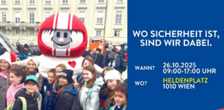 HELMI in einer Menge von Kindern auf dem Heldenplatz in Wien. Der Bildtext: Wo Sicherheit ist, sind wir dabei. Wann? 26.10.2025, 09:00-17:00 Uhr, Wo? Heldenplatz, 1010 Wien