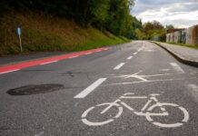 Eine Fahrbahn mit einem breiten Radweg auf der Fahrbahn, einer mittleren Fahrbahn für Autofahrende und einem weiteren Streifen (in rot), der ebenfalls für Fahrradfahrende vorgesehen ist.