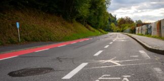 Eine Fahrbahn mit einem breiten Radweg auf der Fahrbahn, einer mittleren Fahrbahn für Autofahrende und einem weiteren Streifen (in rot), der ebenfalls für Fahrradfahrende vorgesehen ist.