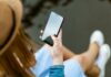 Eine Person mit langen Haaren schaut auf den Bildschirm ihres Smartphones.