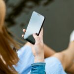 Eine Person mit langen Haaren schaut auf den Bildschirm ihres Smartphones.