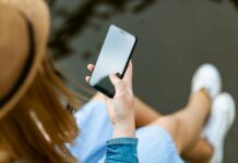 Eine Person mit langen Haaren schaut auf den Bildschirm ihres Smartphones.
