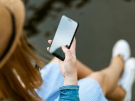 Eine Person mit langen Haaren schaut auf den Bildschirm ihres Smartphones.