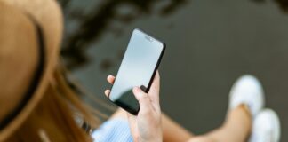 Eine Person mit langen Haaren schaut auf den Bildschirm ihres Smartphones.