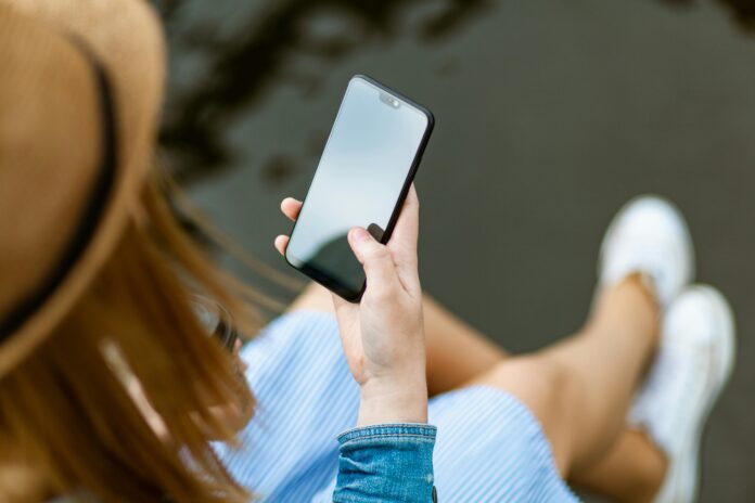 Eine Person mit langen Haaren schaut auf den Bildschirm ihres Smartphones.