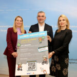 Zwei Frauen und ein Mann halten ein Plakat zur Kampagne hoch. Das Design erinnert an ein Videospiel mit Pixelgrafiken.