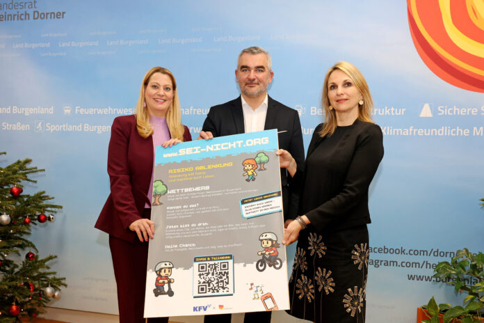 LRin_Winkler_LR_Dorner_KfV_Sei_Nicht_Org_001 Zwei Frauen und ein Mann halten ein Plakat zur Kampagne hoch. Das Design erinnert an ein Videospiel mit Pixelgrafiken.