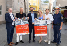 Sechs Personen, die zwei Plakate zu "Achtung Schulkinder" hochhalten für das Land Salzburg und in die Kamera lächeln.
