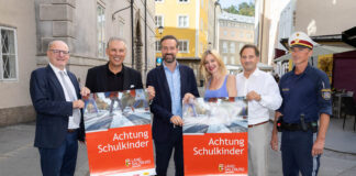 Sechs Personen, die zwei Plakate zu "Achtung Schulkinder" hochhalten für das Land Salzburg und in die Kamera lächeln.